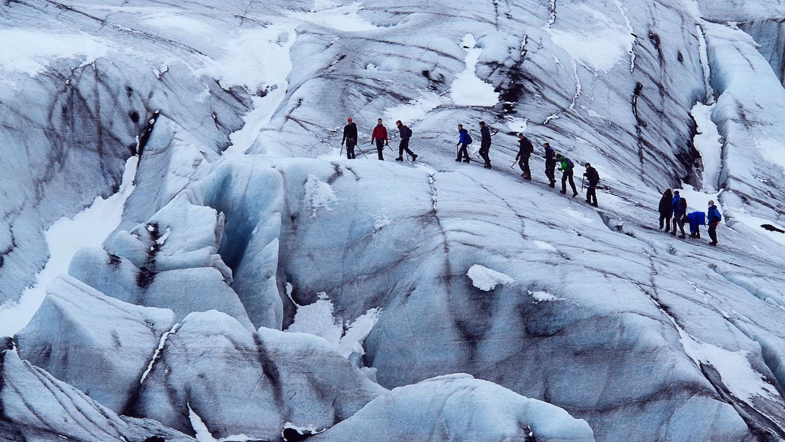 glacier hike group traversing on solheimajokull glacier in colorful jackets