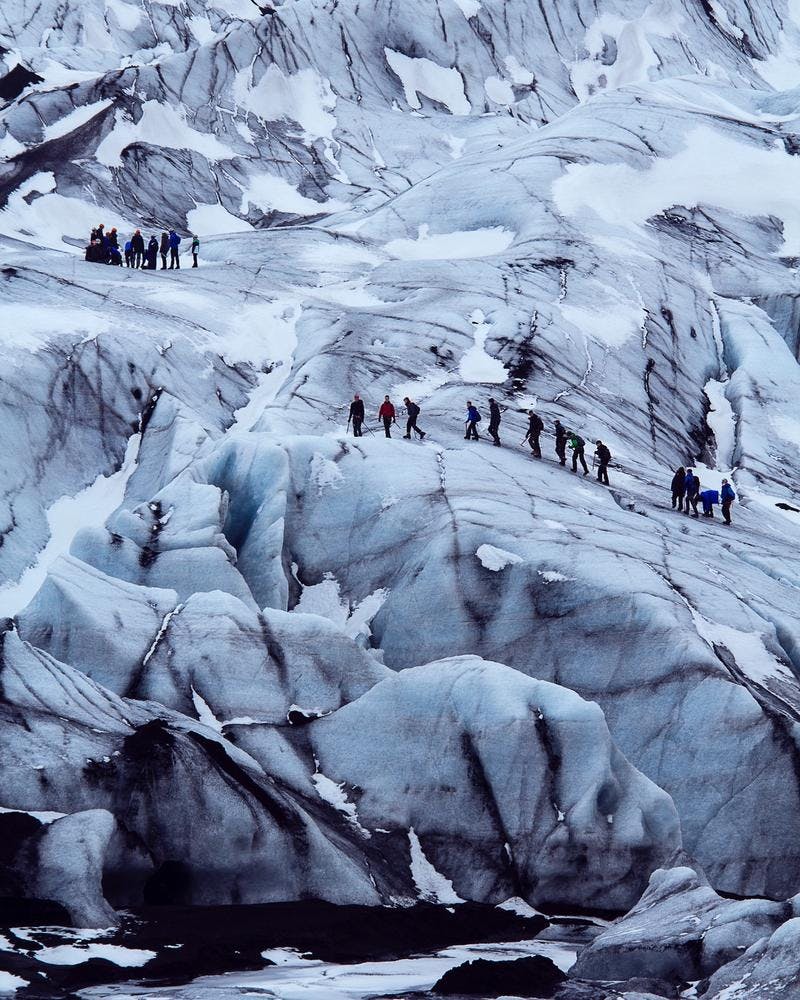 glacier hike group traversing on solheimajokull glacier in colorful jackets