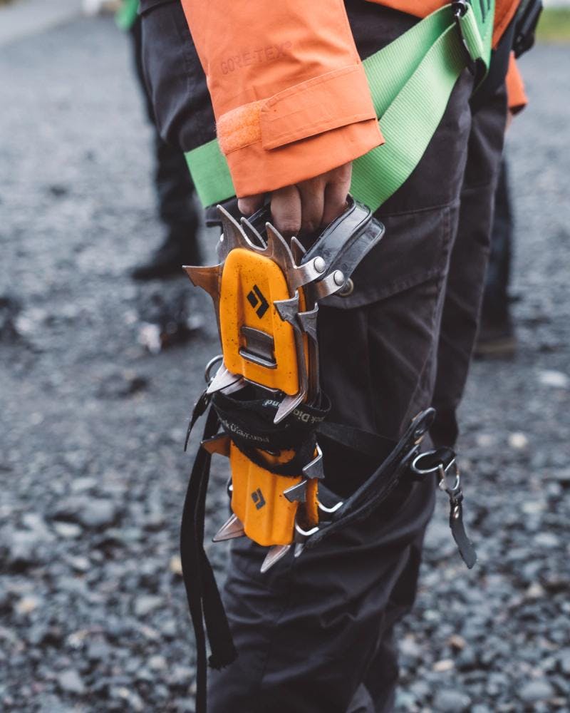 orange crampons strapped on pants of glacier hike tour guide
